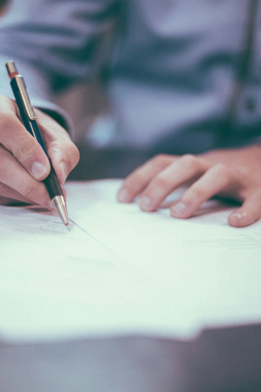 Manos anotando un documento con un bolígrafo durante una revisión lingüística